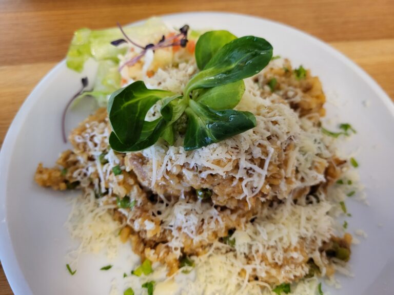 Ječné rizoto se sýrem, zeleninou a polníčkem na bílém talíři – hlavní vegetariánské jídlo BISTRO SOUD